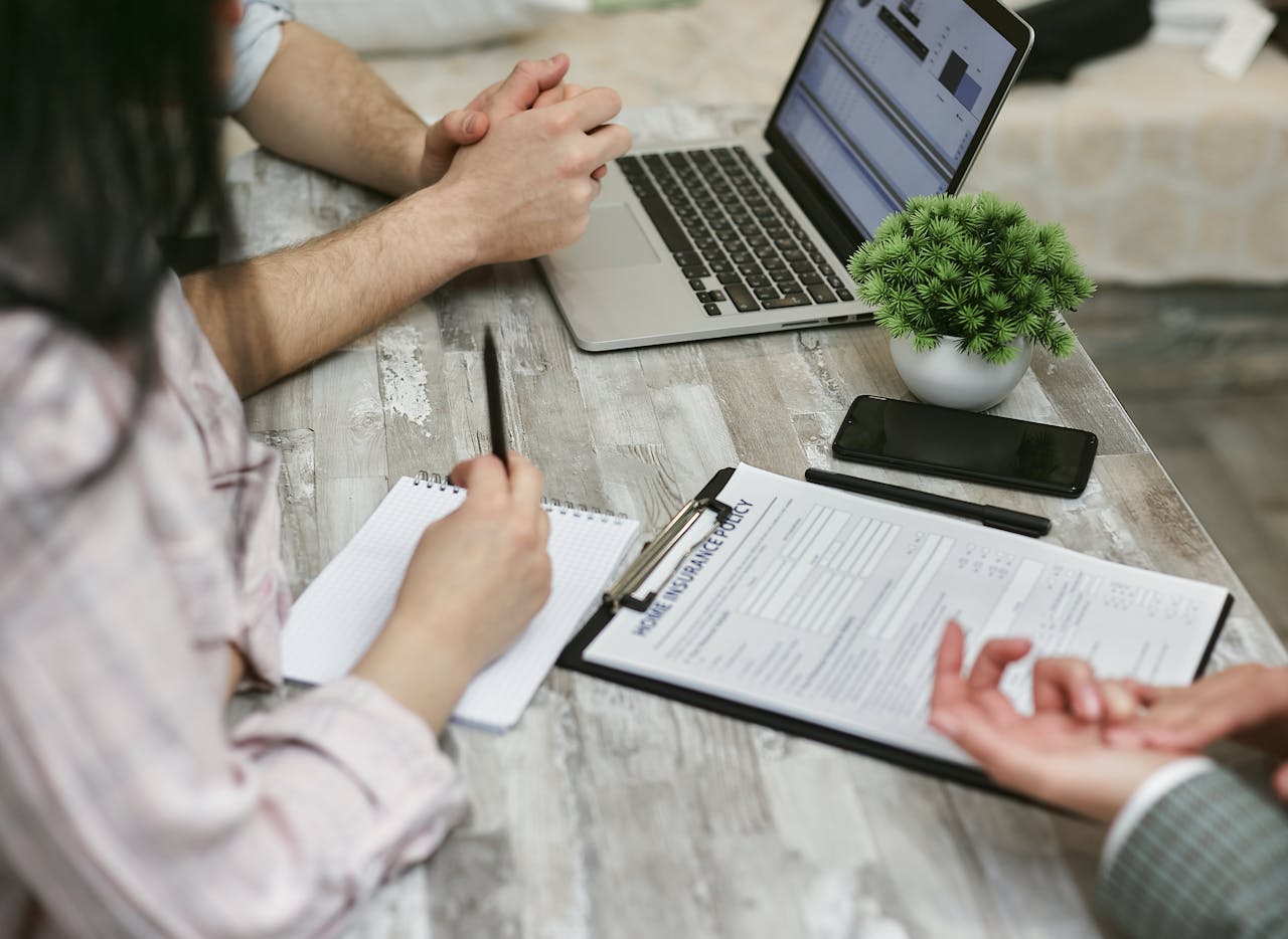 our-story Professionals discussing home insurance policy over laptop and notes in an office setting.